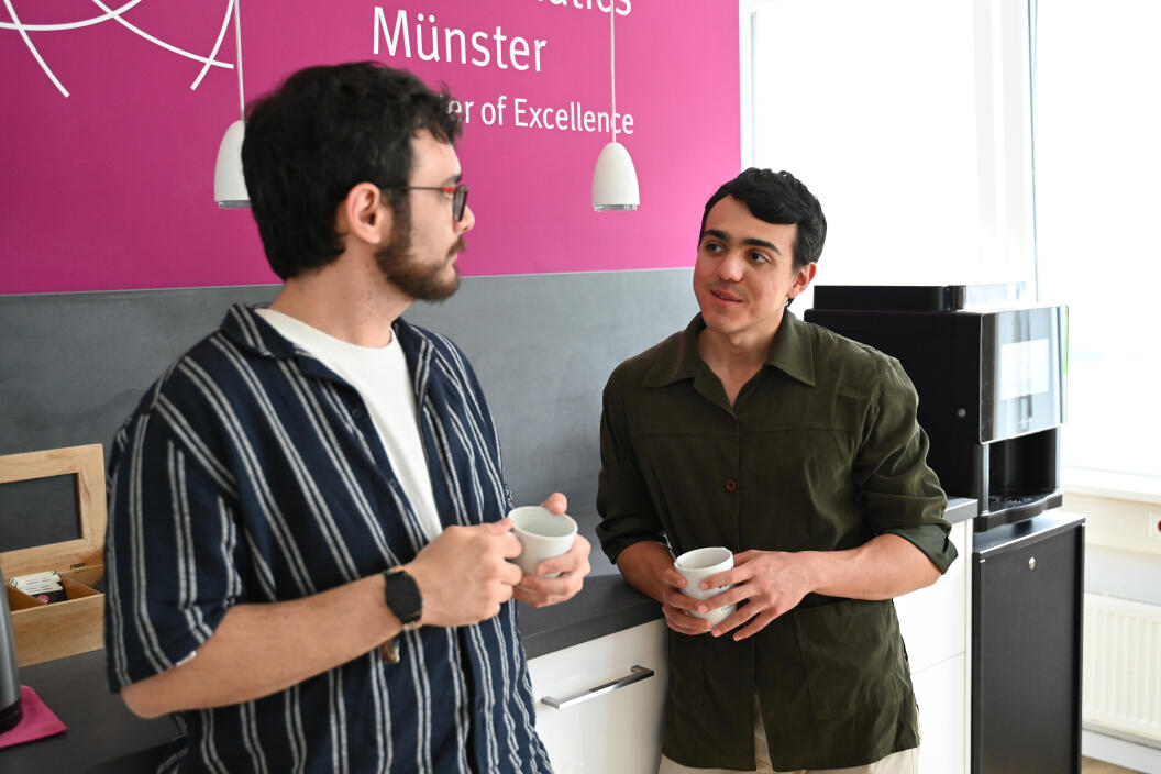 Picture of Simone speaking to a guest of the podcast, holding cups of coffee.